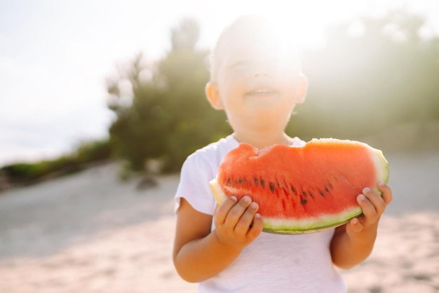 Lustiges Kind auf dem Meer mit Wassermelone Junge, der Wassermelone isst Glückliche Kindheit