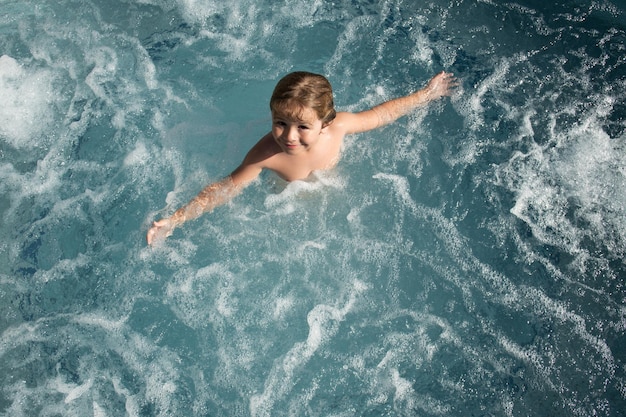 Lustiges Kind, das den Sommer im Whirlpool-Spa des Pools genießt