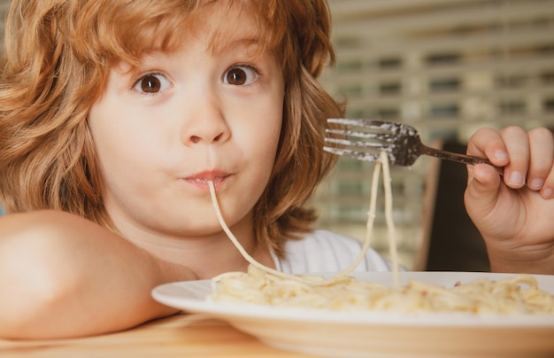 Lustiges Kind, das Pasta-Spaghetti-Gesicht isst, Nahaufnahme, Kinderkopfporträt