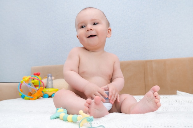 Lustiges Kind lächelt und zeigt Zunge. Babys Milchzähne brechen aus, das Zahnfleisch juckt. Das Kind hat ein Spielzeug im Mund