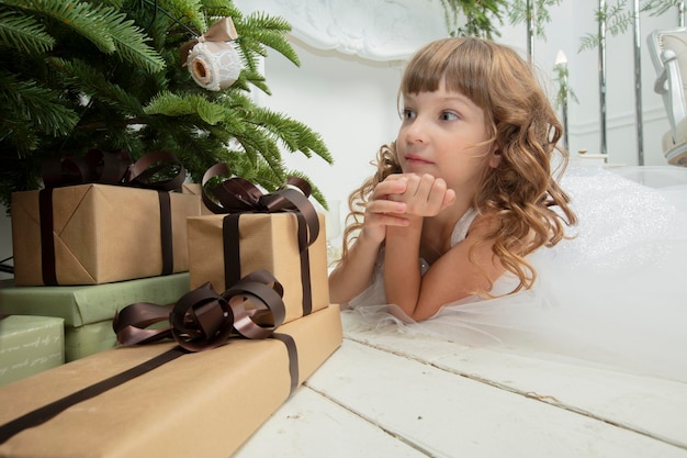 Lustiges Kind zu Weihnachten Mädchen unter dem Weihnachtsbaum mit Geschenken