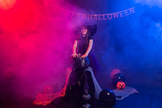 Lustiges Kindermädchen im Hexenkostüm für Halloween mit Kürbis Jack.