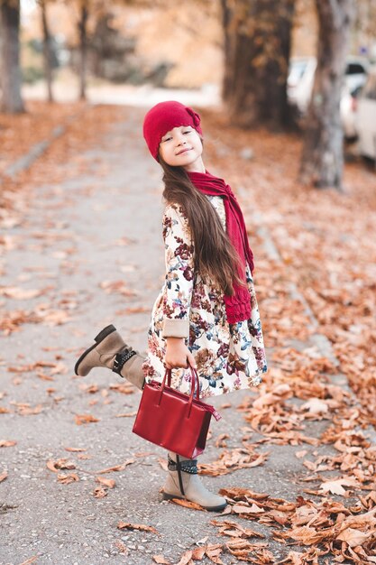 Lustiges Kindermädchen mit Herbstjacke und Strickmütze mit Schal im Park