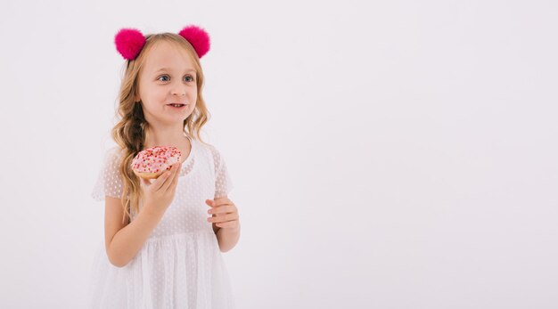 Lustiges kleines Mädchen, das einen Donut auf einem weißen Hintergrund isst