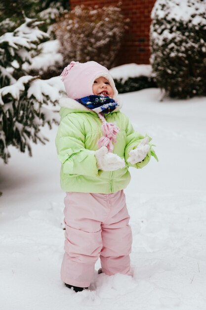 Lustiges kleines Mädchen, das Spaß im schönen Winterpark während hat