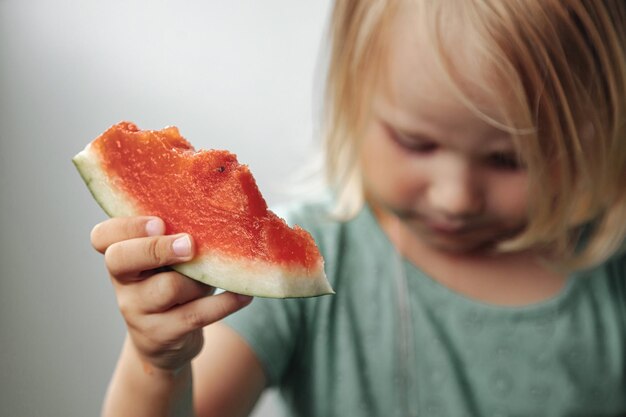 Lustiges kleines Mädchen, das Wassermelonennahaufnahme isst. Nettes Kind mit Wassermelone drinnen. Konzept der gesunden Ernährung, Sommer. Platz kopieren