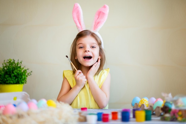 Lustiges kleines Mädchen in Hasenohren bereitet sich auf Ostern vor bemalte Ostereier fröhliches Osterkonzept