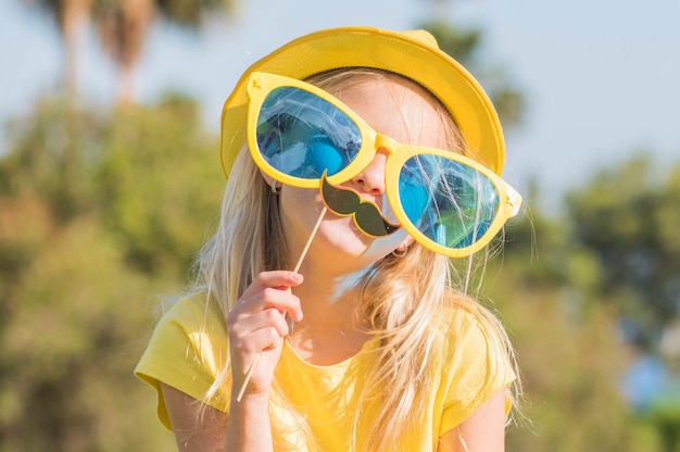 Lustiges kleines Mädchen mit Papiermaske. Kindergeburtstag, Sommerspaß.