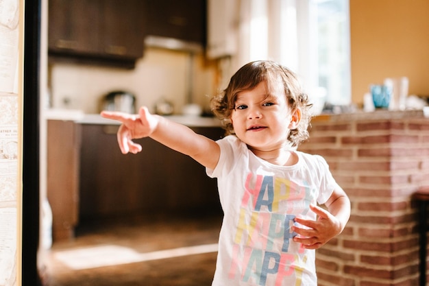 Lustiges Kleinkindmädchen, das drinnen tanzt, kleines Kind spielt Baby, das Spaß hat, sich zu bewegen und auf dem Boden in einer sonnigen weißen Zimmerküche zu Hause oder im Kindergarten zu springen