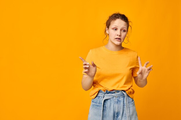 Lustiges Mädchen in einem gelben T-Shirt, das Emotionen aufwirft, isolierte Hintergründe unverändert