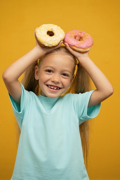 Lustiges Mädchen mit Donuts auf gelbem Hintergrund