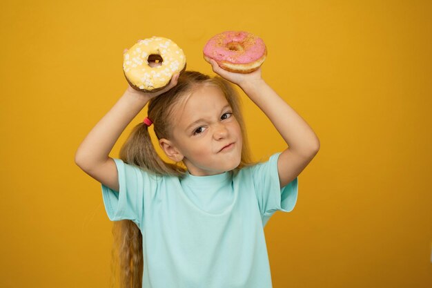 Lustiges Mädchen mit Donuts auf gelbem Hintergrund