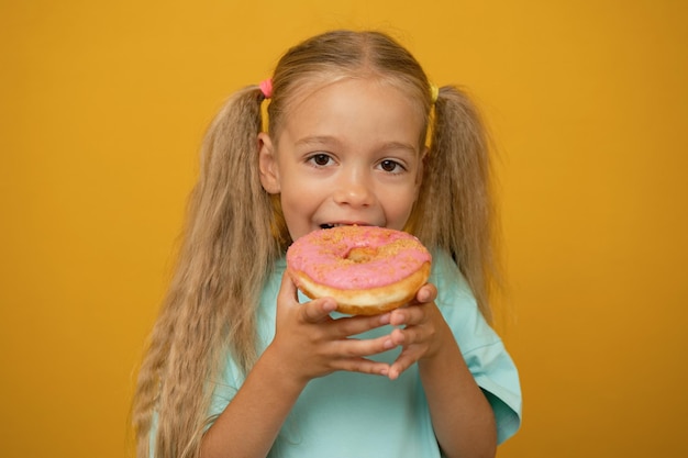 Lustiges Mädchen mit Donuts auf gelbem Hintergrund