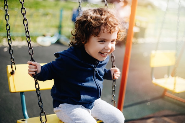 Lustiges niedliches glückliches Baby, das auf dem Spielplatz spielt. Das Gefühl von Glück, Spaß, Freude. Lächeln eines Kindes.