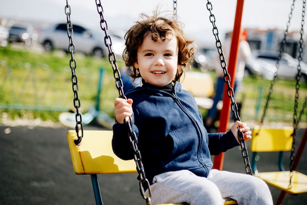 Lustiges niedliches glückliches Baby, das auf dem Spielplatz spielt. Das Gefühl von Glück, Spaß, Freude. Lächeln eines Kindes.