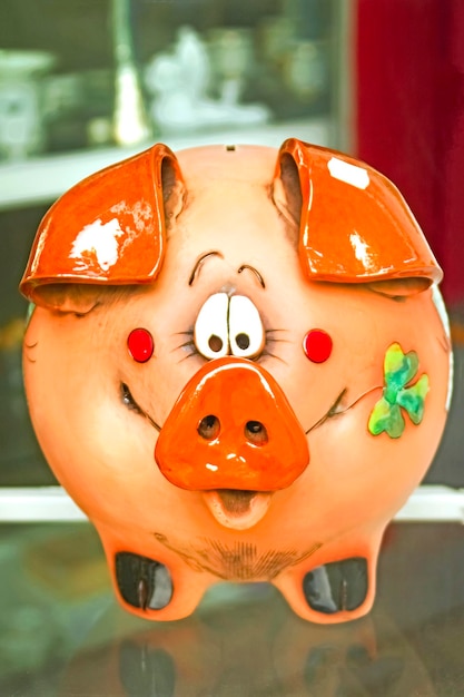 Lustiges orangefarbenes Sparschwein auf einem Glasregal