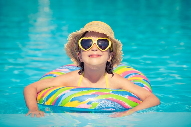 Lustiges Porträt des Kindes Kind, das Spaß im Schwimmbad im Freien hat Sommerurlaub und gesundes Lebensstilkonzept