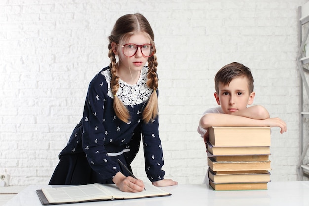 Lustiges Porträt des Schülers und des Schulmädchens mit Buch auf weißem Haupthintergrund