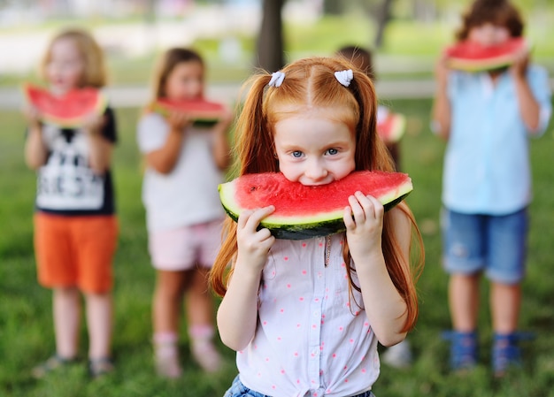 Lustiges rothaariges kleines Mädchen isst gierig saftige reife Wassermelone