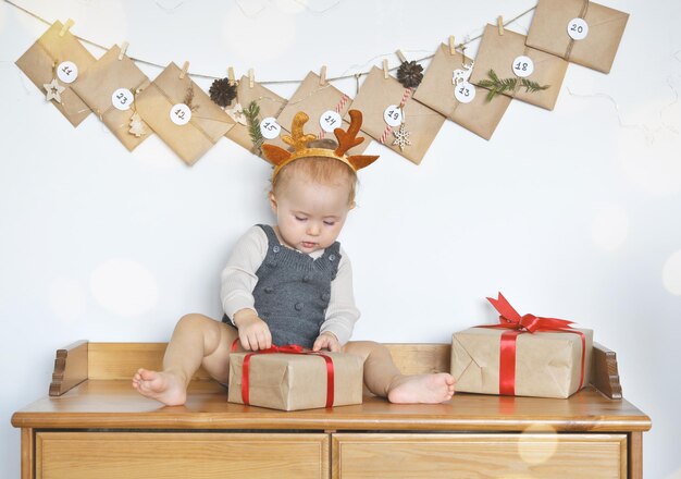 Lustiges Säuglingsbaby packt Weihnachtsgeschenkbox aus. Adventskalender. Frohes neues Jahr. Frohe Weihnachten.