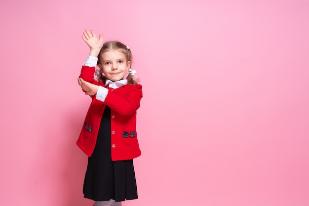 Lustiges Schulmädchen in der Uniform, die Hand anhebt