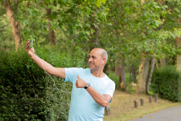 Lustiges Selfie eines haarlosen weißen Mannes, der einen Videoanruf in der Natur macht und in die Kamera lächelt