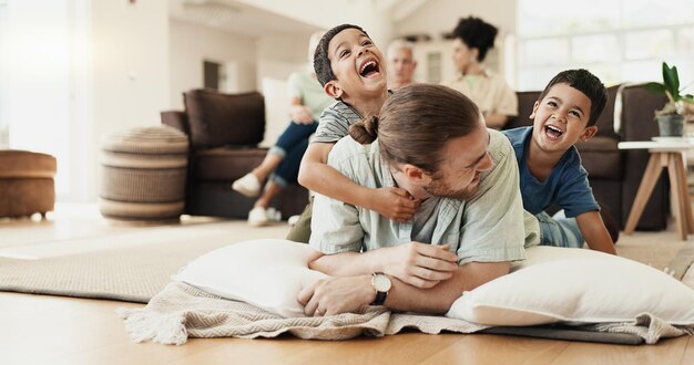 Foto lustiges spiel und vater mit kindern auf dem boden im wohnzimmer lachen über comedy-witz oder humor glücklicher vater und kinder haben spaß, verbinden sich und genießen die familienzeit zusammen im adoptionshaus