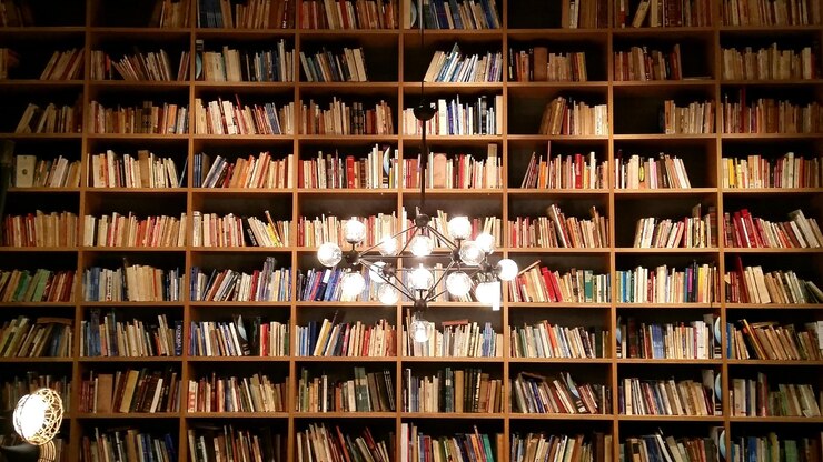 Foto lustre iluminado pendurado contra a estante da biblioteca