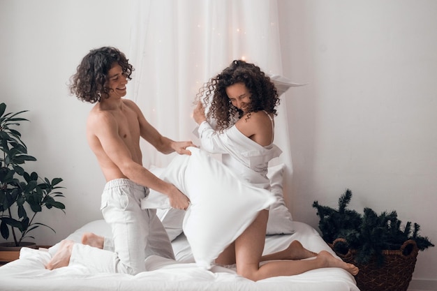 luta de travesseiros - casal amoroso homem e mulher brincando juntos em casa, conceito de relações próximas