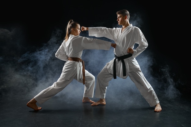 Lutadora de caratê no treinamento com o mestre, quimono branco. Karateka em treino, artes marciais, competição de luta