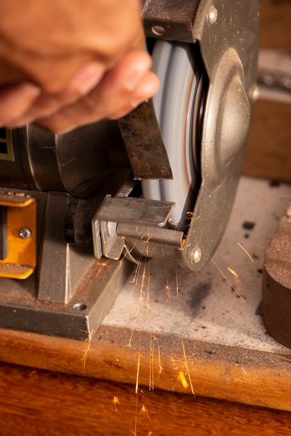 Luthier usando moedor para preparar a peça de metal