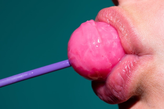 Lutscher im Mund, Nahaufnahme. Schöner Mädchenmund mit Lolli-Pop. Oralsex-Blow-Job-Konzept. Glatte rote Frauenlippen mit Zunge. Mundlecken lutschen Chupa Chups.