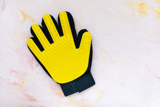 Luva de silicone amarelo para gatos e cães, aliciamento na parede rosa, cópia espaço. cuidados de animais de estimação, massagem de mãos, limpeza e escovação conceito de animais de estimação