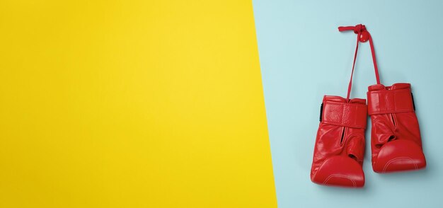 Luvas de boxe de couro vermelho penduradas em um cabo azul de fundo Equipamentos esportivos