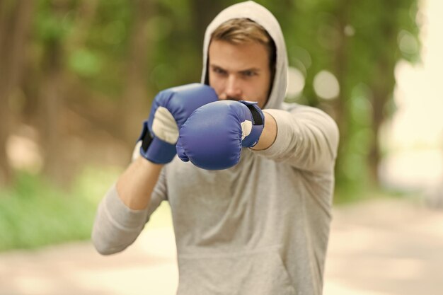 Luvas de boxe de treinamento concentrado de desportista Luvas de esporte de rosto concentrado de atleta praticam habilidades de luta fundo da natureza Ataque ou defesa sempre esteja pronto Boxeador focado no boxe
