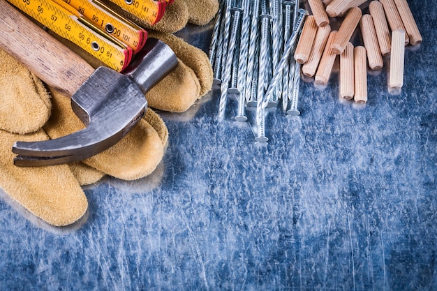 Luvas de proteção de couro martelo pilha de medidores de madeira de pregos de metal e buchas no conceito de construção de fundo metálico riscado