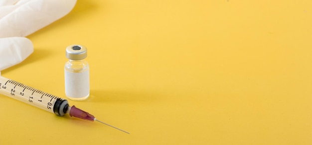 Foto luvas médicas de vacina de perto seringas em fundo amarelo