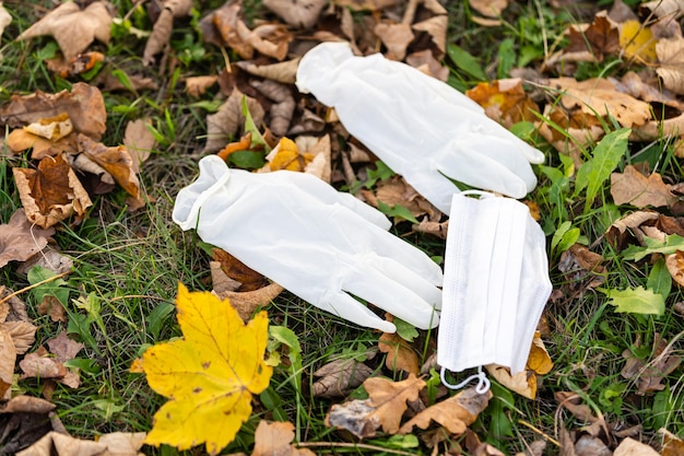 luvas médicas e uma máscara caídas no chão em um parque de outono