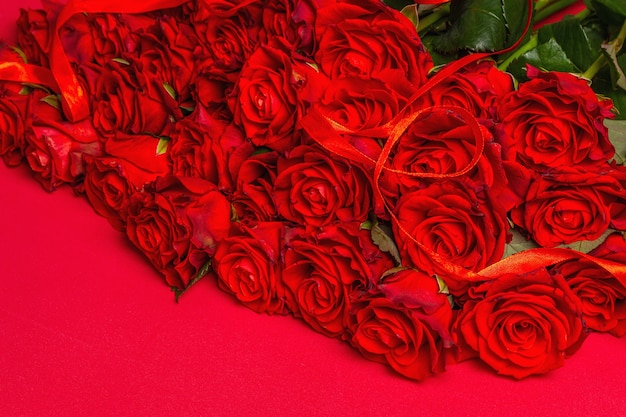 Luxuoso buquê de rosas vermelhas frescas. O conceito festivo para casamentos, aniversários, dia 8 de março, dia das mães ou dos namorados. Cartão de felicitações, fundo vermelho fosco