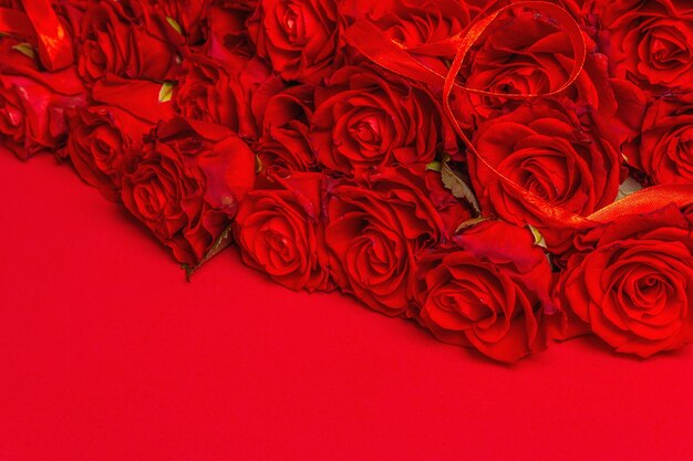 Luxuoso buquê de rosas vermelhas frescas. O conceito festivo para casamentos, aniversários, dia 8 de março, dia das mães ou dos namorados. Cartão de felicitações, fundo vermelho fosco