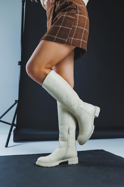 Luxuriöse, elegante, weiße Damenlederstiefel mit flacher Sohle an Damenfüßen Kollektion von Lederschuhen für Damen im Winter