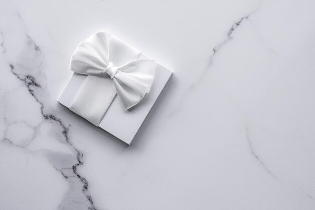 Luxuriöse Hochzeitsgeschenke mit Seidenschleife und Bändern auf Marmorhintergrund