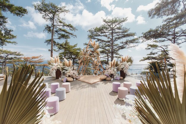 Luxuriöse Hochzeitszeremonie im Boho-Stil auf dem Hintergrund des Waldes und des Ozeans.
