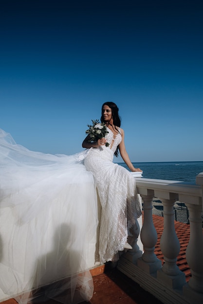 Luxuriöse junge Braut in einer teuren modischen Garderobe posiert für ein Hochzeitsfotoshooting in einer luxuriösen Ferienstadt