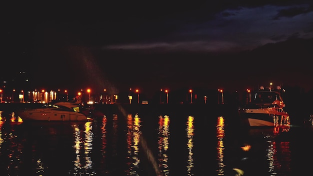 Luxuriöse, moderne Privatyacht und Boot am Pier bei Nacht Schiff überquert die Skyline im Hafen