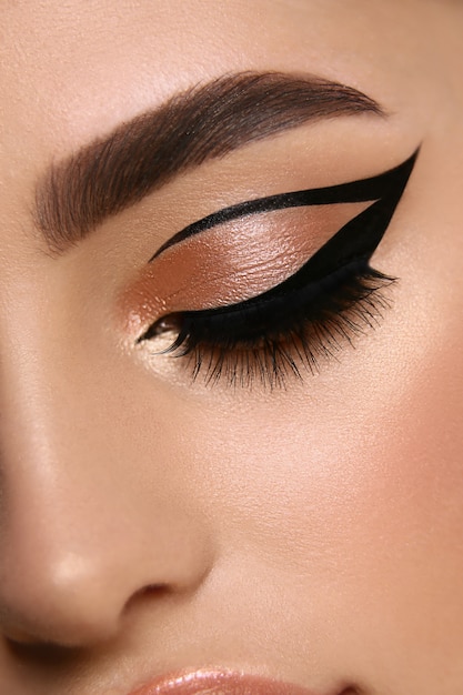 Luxuriöse weibliche Make-up-Nahaufnahme mit Eyeliner und goldenem Lidschatten