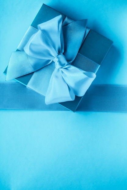 Luxuriöse Weihnachtsgeschenke mit Seidenband und Schleife auf blauem Hintergrund