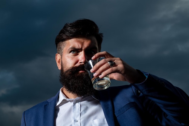 Luxuriöser reicher bärtiger Mann trinkt teures Getränk Mann mit Bart hält Glasschnapsgetränk Cognac Guy
