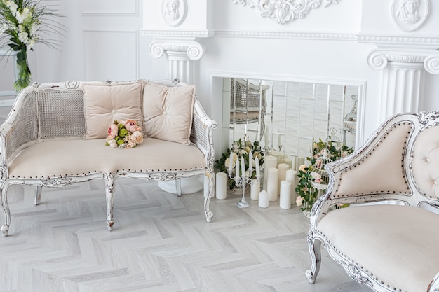 Luxuriöses helles geräumiges Gästezimmer mit schönen schicken Möbeln ein riesiges raumhohes Fenster im königlichen Stil ist mit grünen Pflanzen dekoriert, weiße Wände mit Stuck und ein Kamin