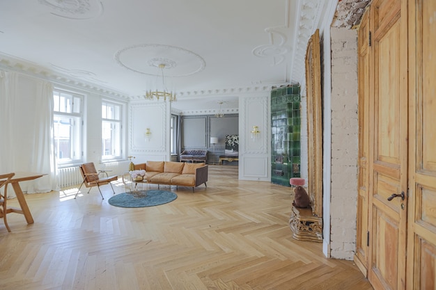 Luxuriöses Interieur einer geräumigen Wohnung in einem alten historischen Haus aus dem 19. Jahrhundert mit modernen Möbeln. hohe Decke und Wände sind mit Stuck verziert